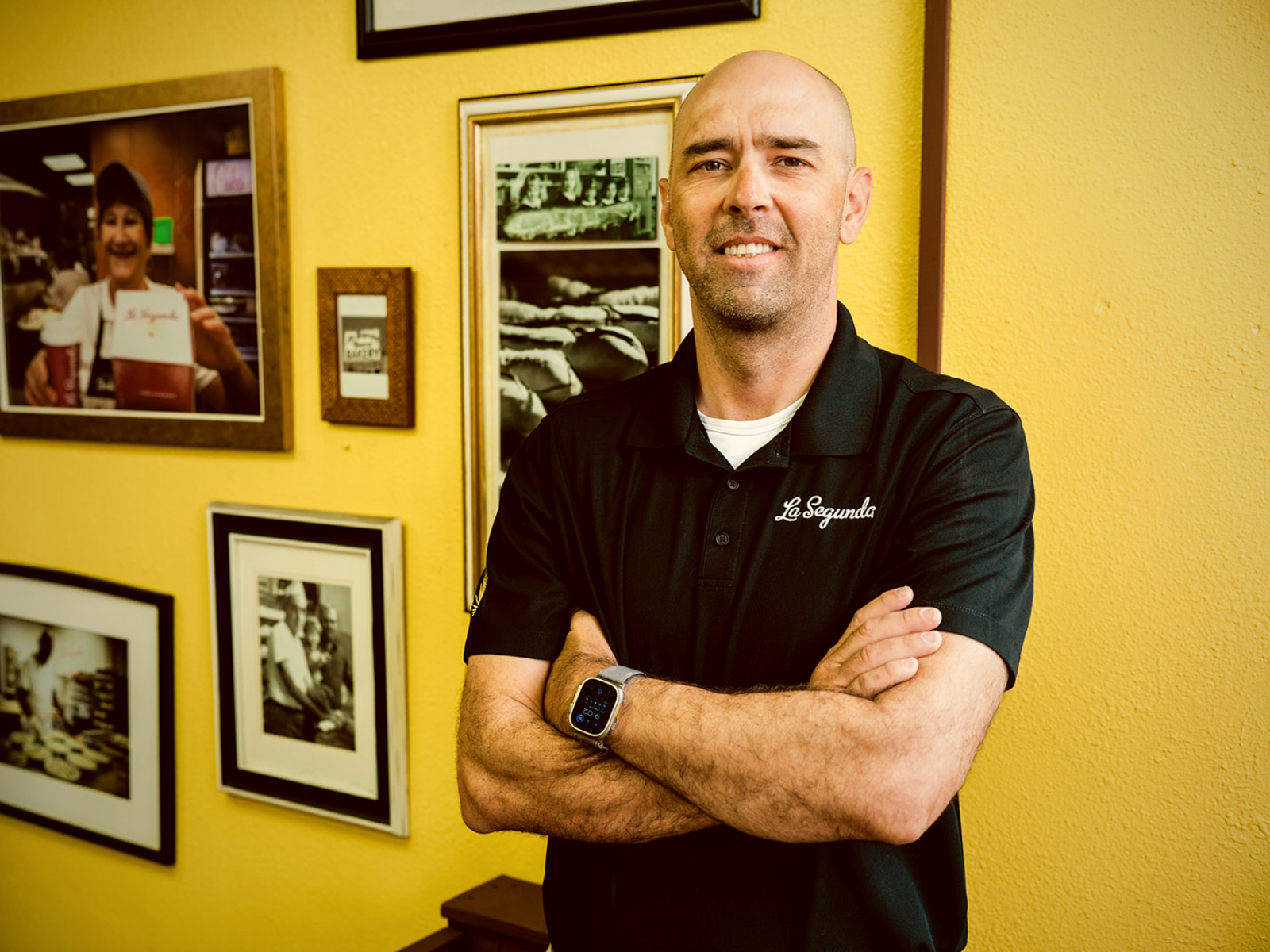 Anthony Copeland Moré, fourth-generation owner of La Segunda, photographed inside the bakery beside the wall of family history.