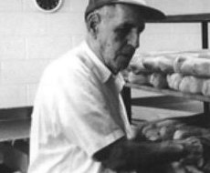 A second-generation Moré baker loading fresh-baked Cuban bread loaves onto cooling racks.
