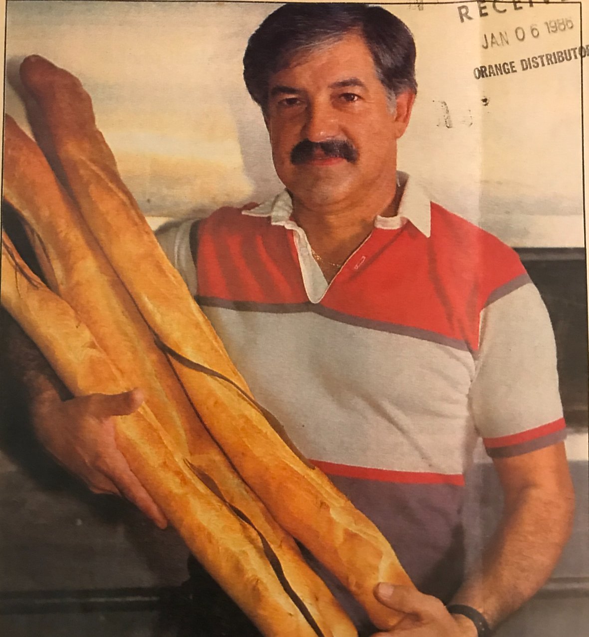 Raymond Moré, third-generation owner of La Segunda, holding fresh-baked Cuban bread loaves in a 1986 newspaper feature.