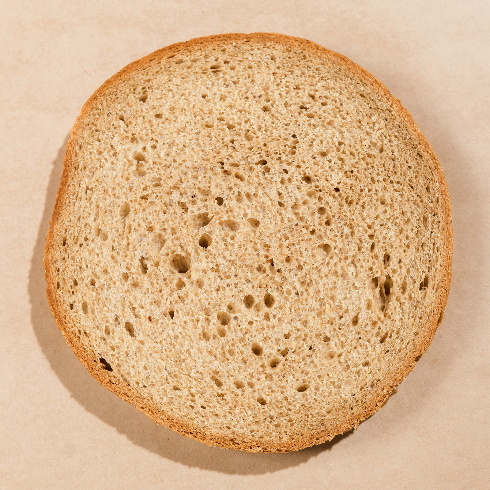 Round cross-section slice of La Segunda wheat bucket bread, tan whole-grain crumb.